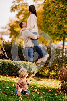 cute little one on walk with mom and dad on lawn in fall park. selective focus.