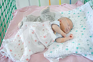 Cute little peaceful baby calm sleeps soundly in his crib in a bright room.