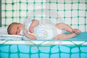 Cute little peaceful baby calm sleeps soundly in his crib in a bright room