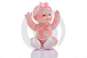 Cute little plastic baby doll with blue eyes sitting isolated o