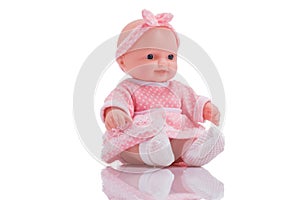 Cute little plastic baby doll with blue eyes sitting isolated o