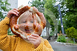 Cute little preschool child, holding big pretzel, eating