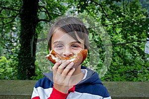 Cute little preschool child, holding big pretzel, eating