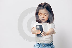 a cute little preschool girl stands on a white background in a white T-shirt and takes pictures of herself on her