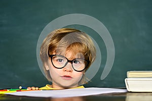 Cute little preschool kid boy in a classroom. Blackboard background. Teachers day. Kids from primary school. September 1