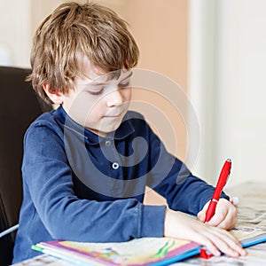 Cute little preschool kid boy at home making homework, writing letters with colorful pens. Little child doing excercise
