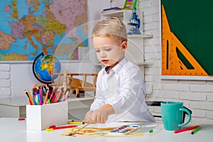 Cute little preschool kid boy with teacher study in a classroom. Elementary school and education. After school teaching.