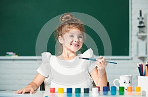 Cute little preschooler child girl drawing at school. Child girl painting on elementary school. Funny kids emotions.