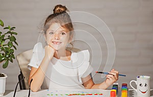 Cute little preschooler child girl drawing at school. Child girl painting on elementary school. Funny kids face.