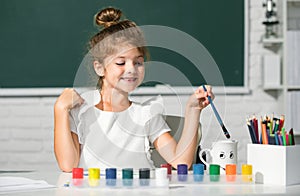 Cute little preschooler child girl drawing at school. Child girl painting on elementary school. Kids creative growth.