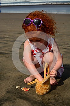 Cute little redhead girl has found shells on the Bali beach