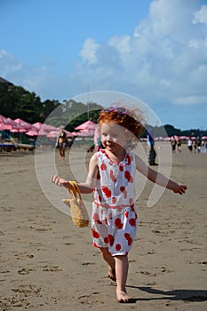 Cute little redhead girl runs on the Bali beach