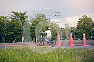Cute little school boy child in safety helmet wearing knee pads, elbow pads and cycling gloves riding a bike on nature