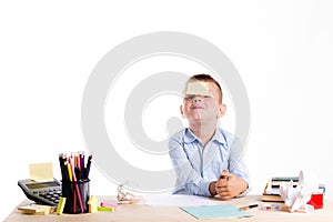 Cute little school boy with huge smile sitting at his desk on white background. Happy intelligent children in shirt with blue eye