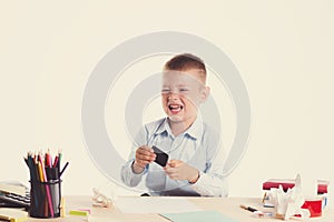 Cute little school boy with sad face sitting at his desk on white background.Unhappy intelligent children in shirt with blue eyes