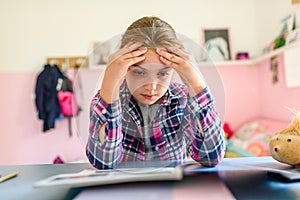 Cute little school girl studying at home in her room. Girl doing homework at home.