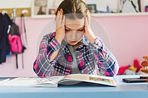 Cute little school girl studying at home in her room. Girl doing homework at home.