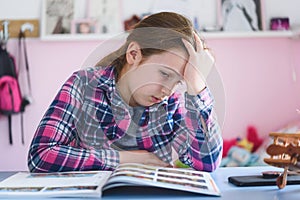 Cute little school girl studying at home in her room. Girl doing homework at home.