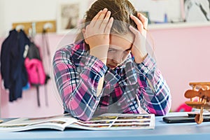 Cute little school girl studying at home in her room. Girl doing homework at home.