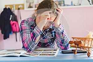 Cute little school girl studying at home in her room. Girl doing homework at home.