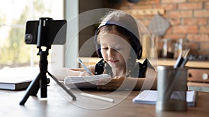 Cute little school pupil girl learning on internet from home