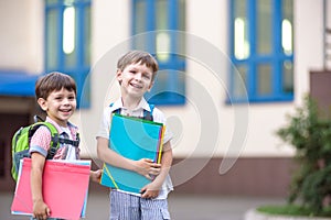 Cute little school students briskly talk on the schoolyard. Chil