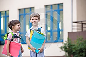 Cute little school students briskly talk on the schoolyard. Chil