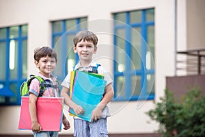 Cute little school students briskly talk on the schoolyard. Children have a good mood. Warm spring morning.