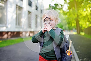 Cute little schoolboy with magnifying glass outdoors on sunny day. Back to school concept.