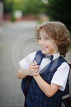 Cute little schoolboy standing on the sidewalk.