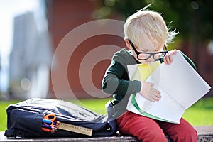 Cute little schoolboy studying outdoors on sunny day. Back to school concept.