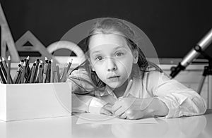 Cute little schoolgirl drawing an house and looking at camera