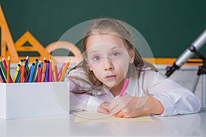 Cute little schoolgirl drawing an house and looking at camera