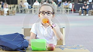 Cute little schoolgirl eating from lunch box outdoor sitting on a school cafeteria. Food for kids