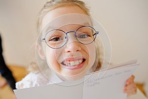 Cute little schoolgirl in glasses shows her copybook.