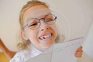 Cute little schoolgirl in glasses shows her copybook.