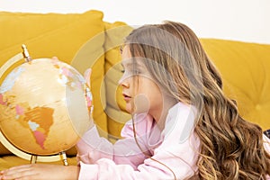 Cute little schoolgirl looking at the globe and learning - children's education concept