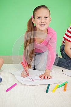 Cute little schoolgirl smiling at camera while drawing