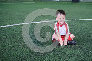 Cute little smiling Asian kindergarten kid, football player in soccer uniform is playing football at Training Session, Soccer