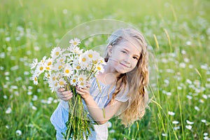 Cute little smiling girl in the chamomile field