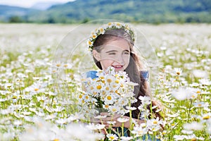 Cute little smiling girl in the chamomile field