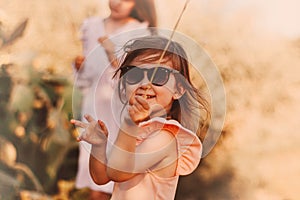 Cute little smiling toddler girl wearing sunglasses and casual dress looking at camera