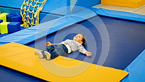 Cute little tired boy lying on trampoline after palying and jumping at playground