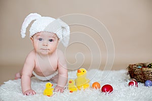 Cute little toddler baby boy, playing with colorful easter eggs