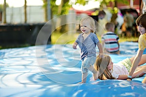 Cute little toddler boy bouncing on huge water filled jumping pillow. Boy jumping up and down on bouncy pad. Active family leisure