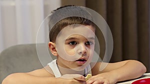 Cute little toddler boy eating at home.