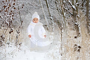 Cute little toddler boy and his older brothers, playing outdoors with snow on a winter day