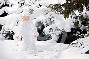 Cute little toddler boy, playing outdoors with snow on a winter day