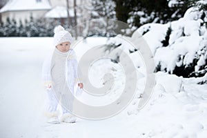 Cute little toddler boy, playing outdoors with snow on a winter day