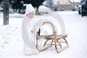 Cute little toddler boy, playing outdoors with snow on a winter day